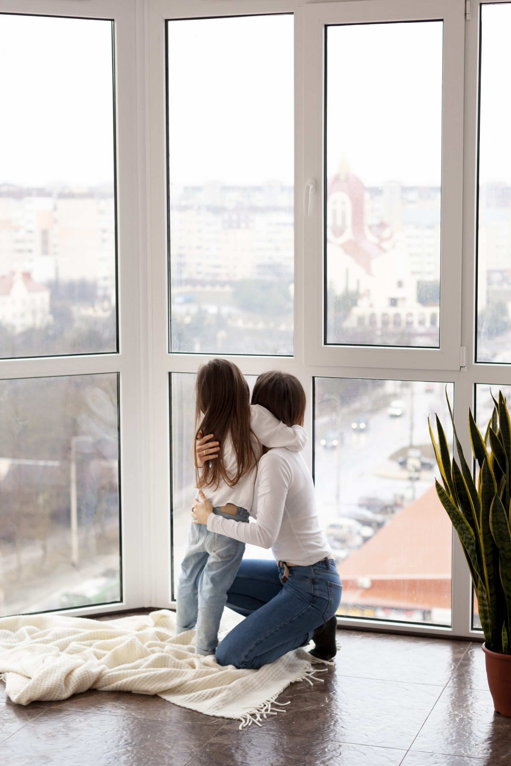 Mujer y niña mirando por ventana de aluminio